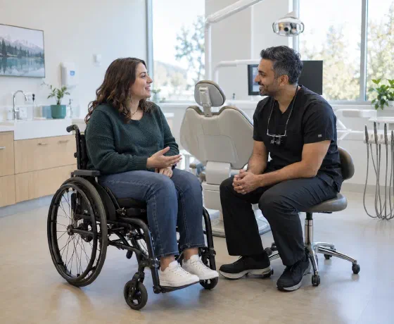 A wheelchair user speaking with a dentist seated at the same eye level